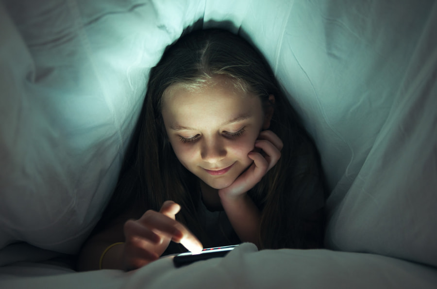 Jeune fille utilisant un téléphone au lit par George Mdivanian sur 500px.com