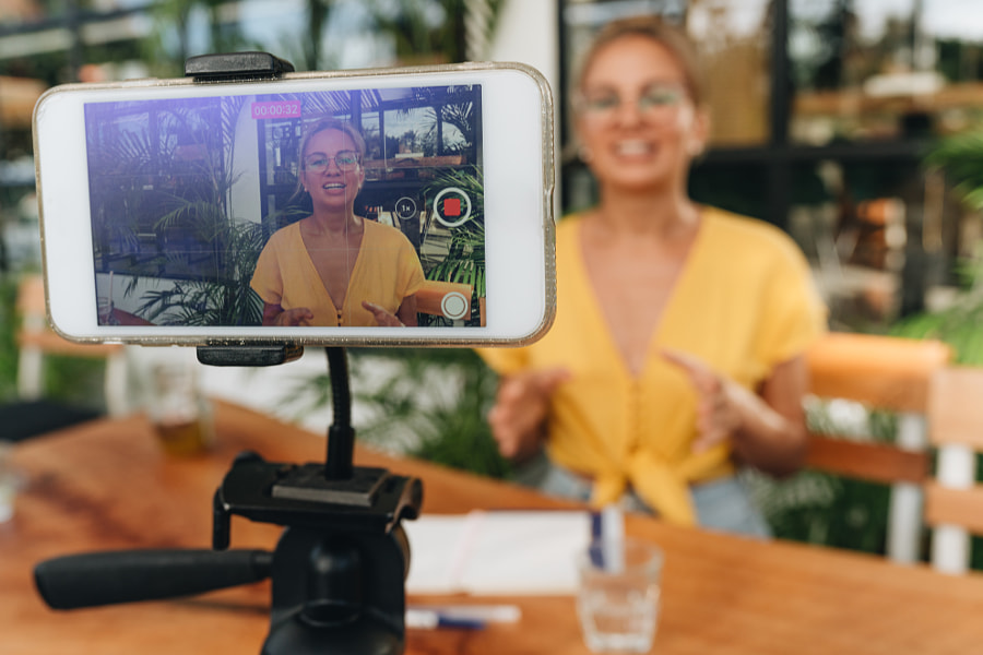 Influenceur Happy vlogger enregistrant des vidéos avec un smartphone sur un tripode. par Natalie Zotova sur 500px.com